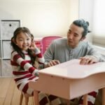 A father and daughter in matching pajamas playing a toy piano, enjoying quality time indoors.