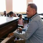 Music teacher engages students with lively piano performance in classroom setting.